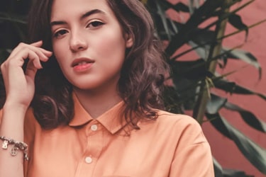 Pretty girl with pastel orange button-up blouse and a charm bracelet